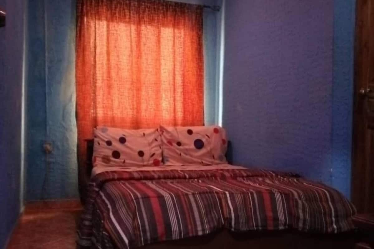 Une chambre à coucher avec un lit, des rideaux et un sol carrelé.