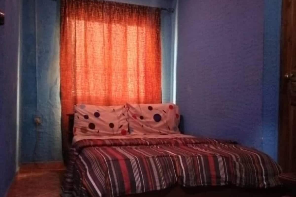 Une chambre à coucher avec un lit, des rideaux et un sol carrelé.