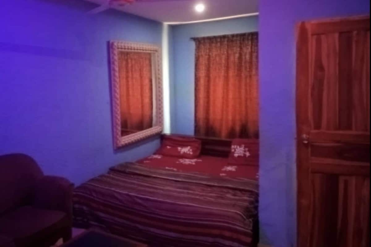 Une pièce avec un lit, une chaise et une porte.