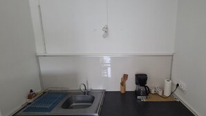 Una cocina compacta con un lavamanos, una cafetera y una pequeña encimera.