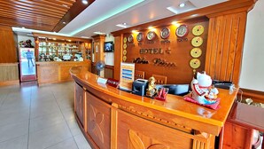 A hotel reception desk with clocks displaying various cities, a cash register, and a decorative cat figurine. - Hien Lam Hotel (Ho Chi Minh City)