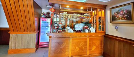 Un área de recepción con un refrigerador de Coca-Cola, mostrador de madera y diversos objetos decorativos.