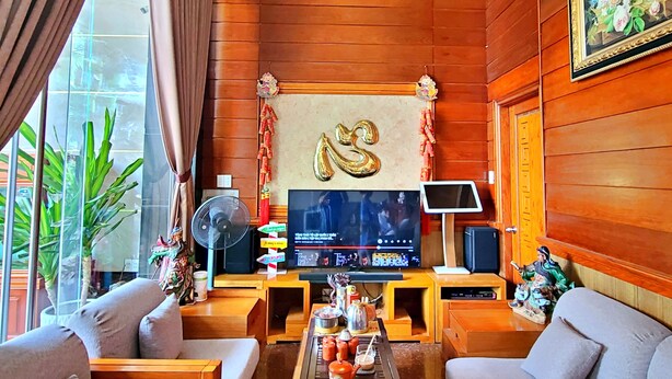 A cozy living room with wooden paneling, a large TV, and a coffee table with various items. - Hien Lam Hotel (Ho Chi Minh City)