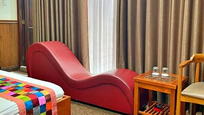A hotel room with a bed, a red lounge chair, a small wooden table with glasses, and a window with curtains. - Hien Lam Hotel (Ho Chi Minh City)