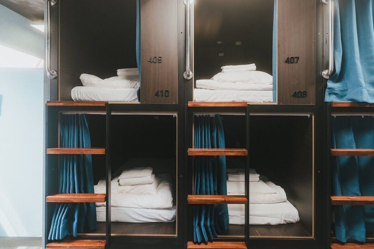 A set of bunk beds with numbers 409, 407, and 410, each with a blue curtain and neatly folded white linens.