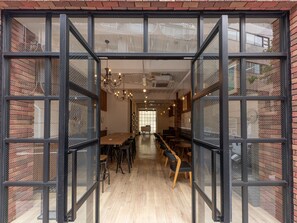 An interior with a long wooden table and chairs, a chandelier, and brick walls. - Hostel JAZ (Tokyo)