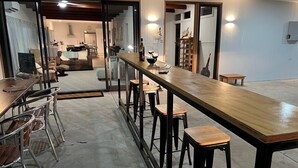 A modern kitchen with a long wooden bar, stools, and a dining table. - Wow! Kangaroo Island – Wildlife, Sunrises, Stunning Views, Spacious -Sleeps 13 (American River)