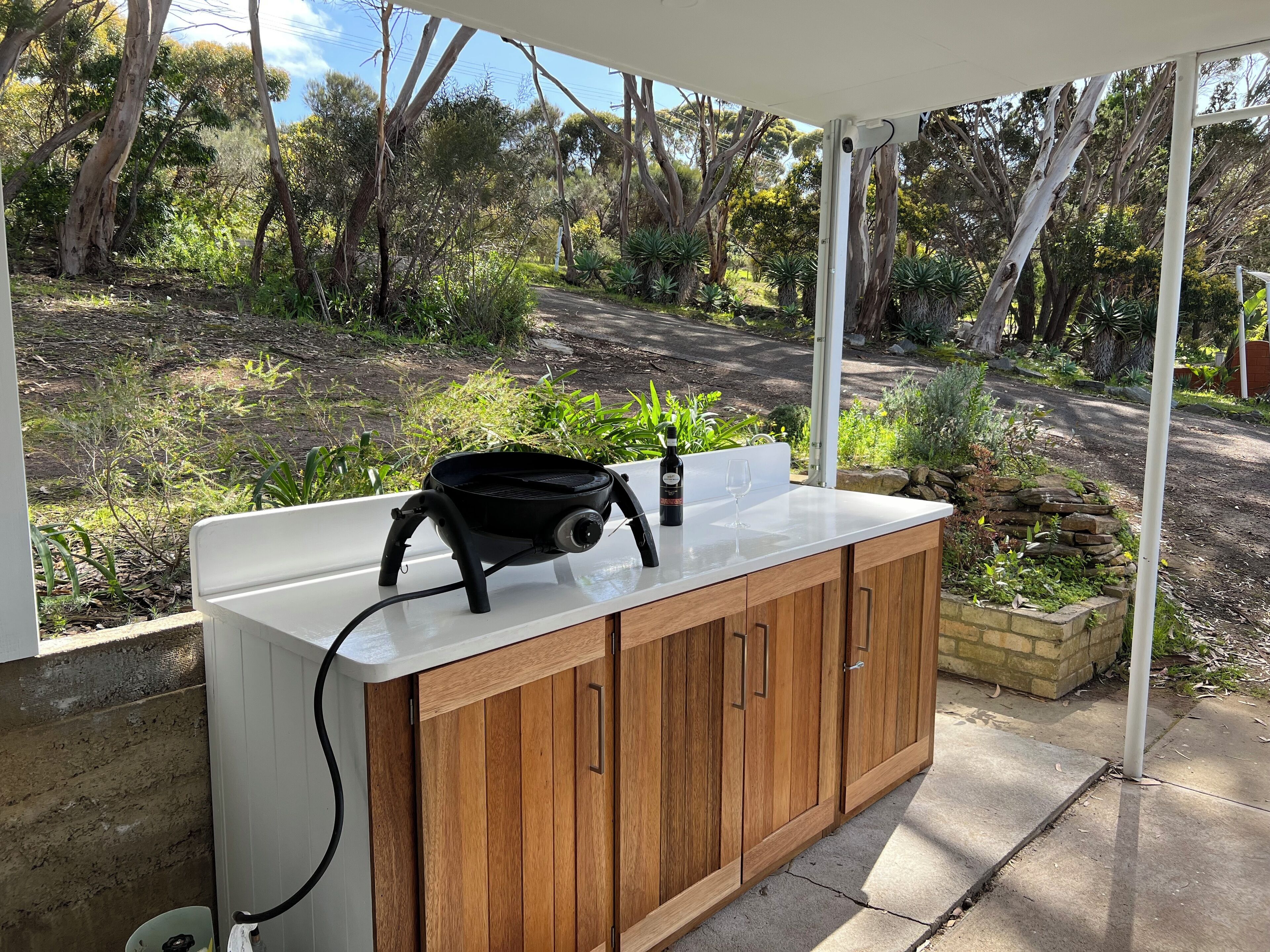 A kitchen area with a white countertop, wooden cabinets, and a grill.