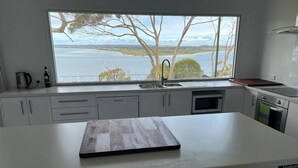 A kitchen with a large island, a view of the sea, and a window. - Wow! Kangaroo Island – Wildlife, Sunrises, Stunning Views, Spacious -Sleeps 13 (American River)