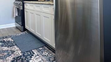 A kitchen with white cabinets, a stainless steel refrigerator, a microwave, and a stove.