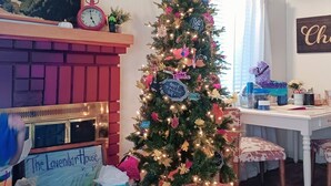 Une pièce chaleureuse avec un sapin de Noël décoré, une cheminée et un tableau accroché au mur.