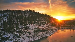 Un paysage hivernal avec une rivière, des arbres couverts de neige et un pont.
