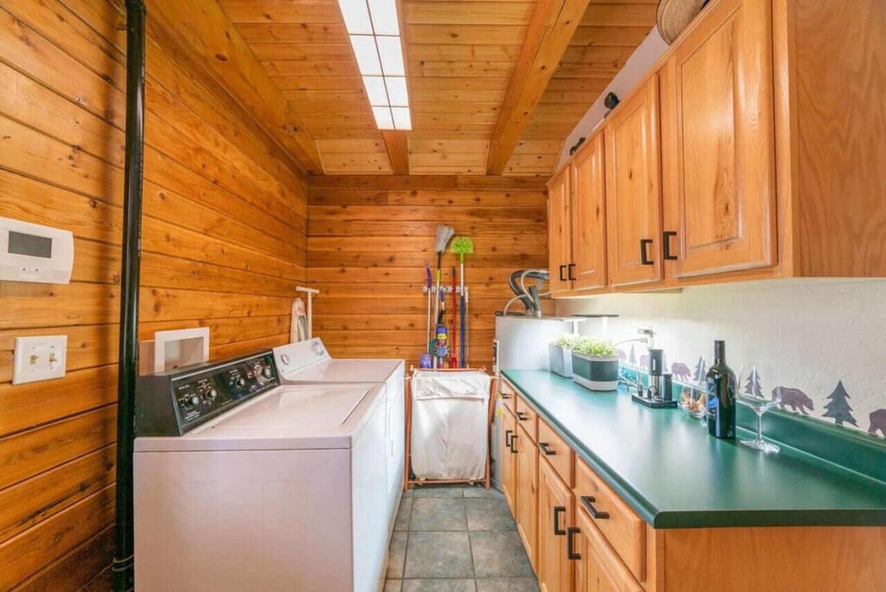 A compact kitchen with wooden cabinets, a washing machine, and a microwave.