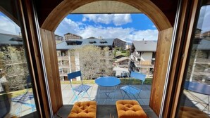 Ein Zimmer mit Blick auf einen Innenhof, ausgestattet mit einem runden Tisch, zwei blauen Stühlen und zwei orangefarbenen Sitzgelegenheiten.
