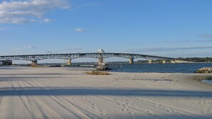 Uma ponte sobre um rio, com uma praia de areia em primeiro plano.