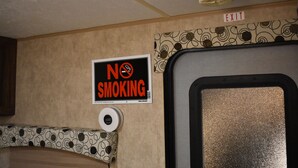 Un panneau «interdiction de fumer», un panneau indiquant la sortie et un distributeur de papier toilette dans une pièce.