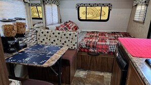 Une cuisine compacte intégrée dans un camping-car, avec deux lits, une machine à café et un petit coin repas.