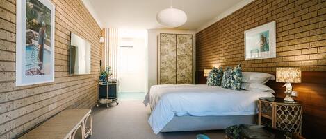 A hotel room with a bed, a bench, a small table, and a nightstand.
