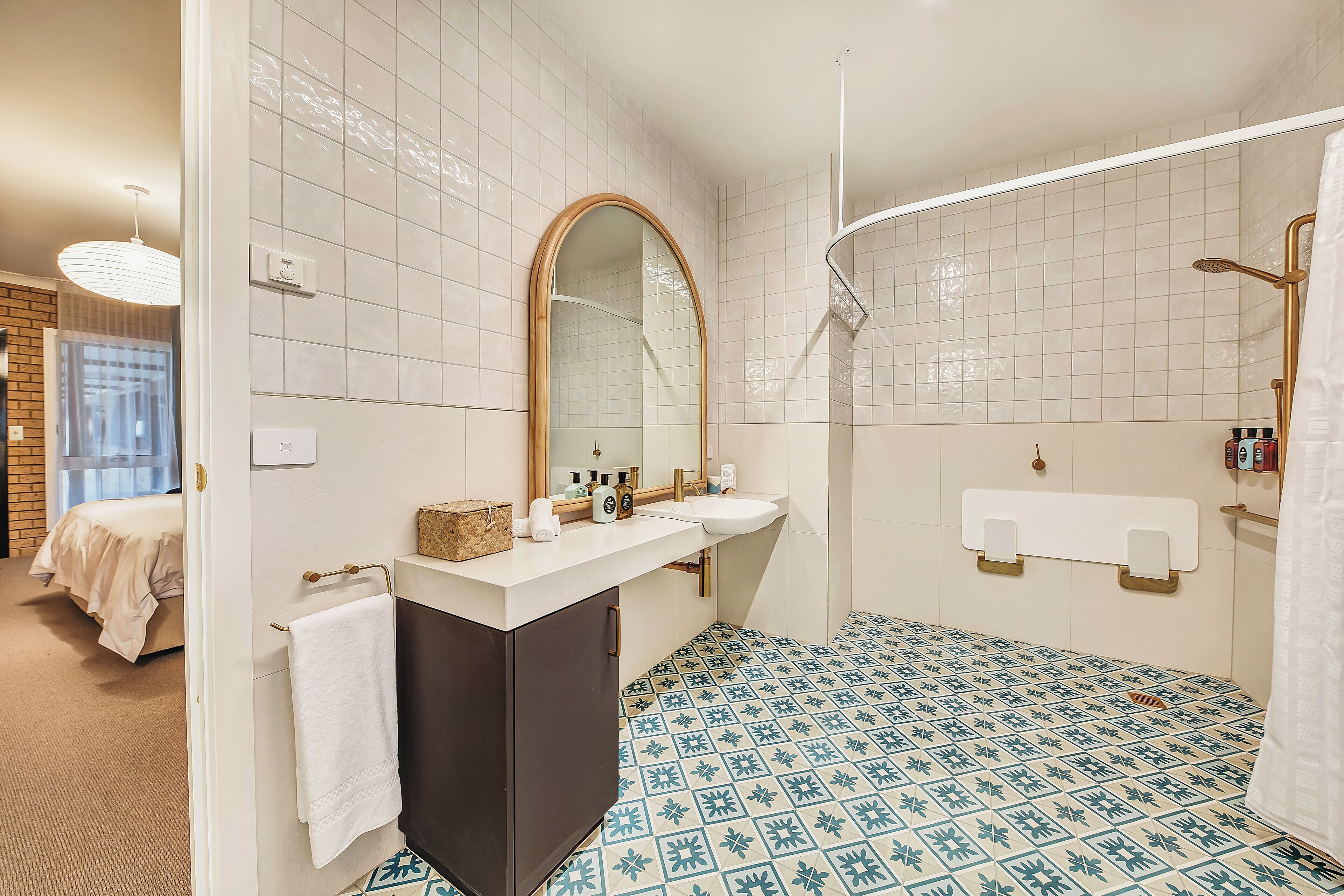 A bathroom with a white sink, a mirror, a towel rack, and a shower area.