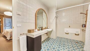 A bathroom with a white sink, a mirror, a towel rack, and a shower area.
