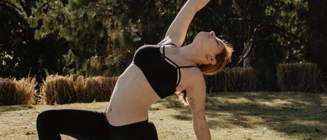 A person performing a yoga pose on a mat outdoors.