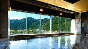 A hot spring area with a view of mountains and a glass wall. - Ooedo Onsen Monogatari Kounkaku (Osaki)