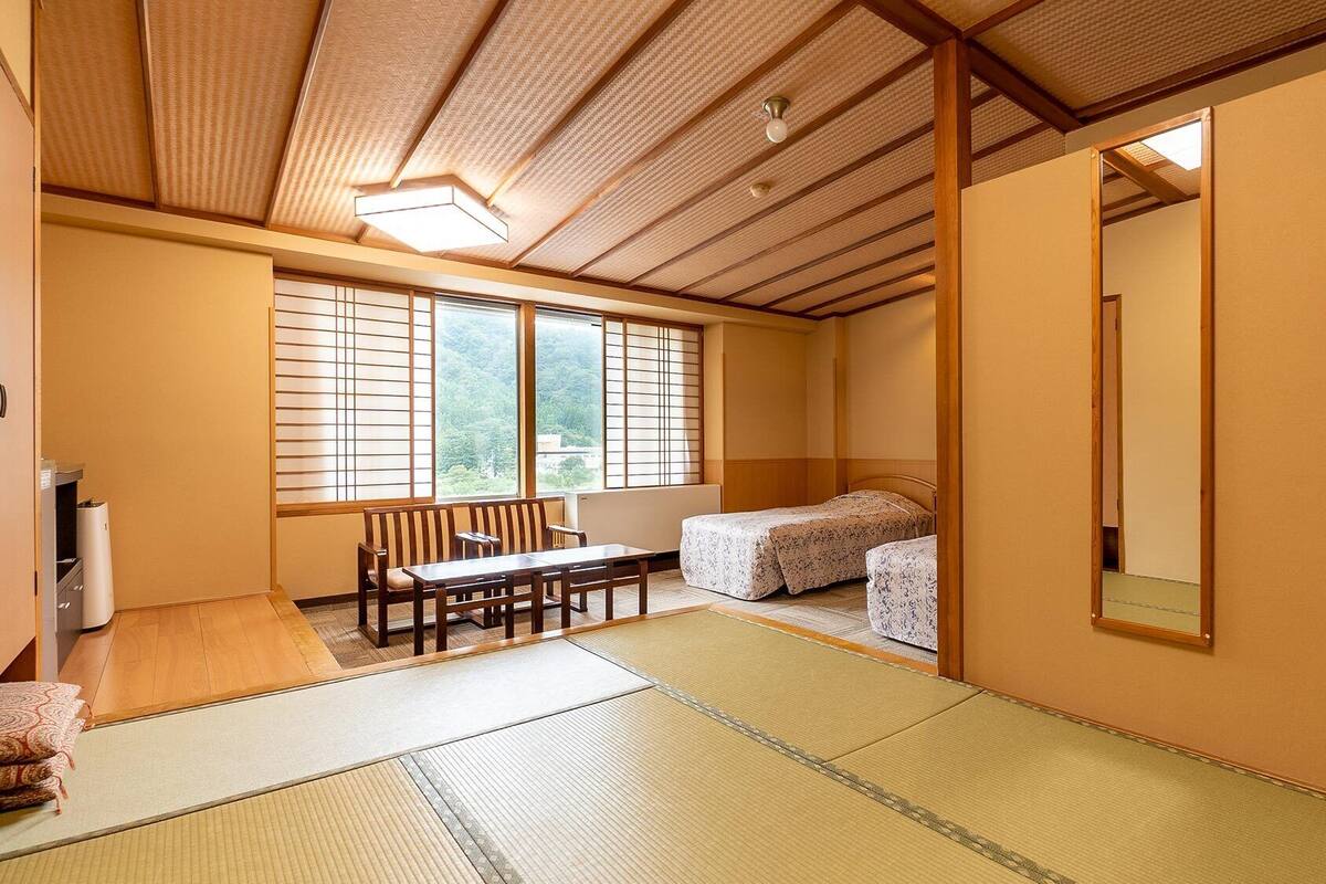 Una habitación japonesa tradicional con suelo de tatami, una mesa baja, un sofá y una cama.