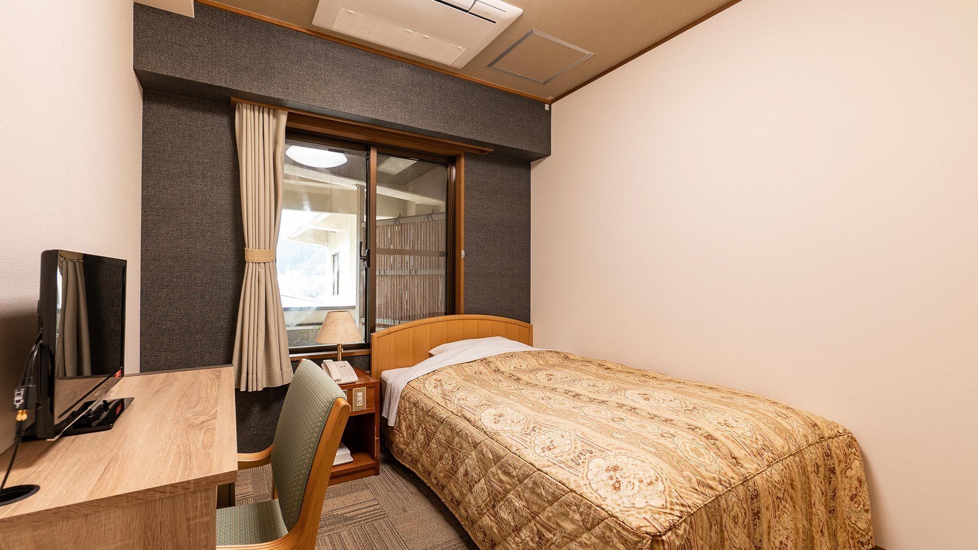 Une chambre d’hôtel avec un lit, un bureau, une chaise, une télévision et une fenêtre avec des rideaux.