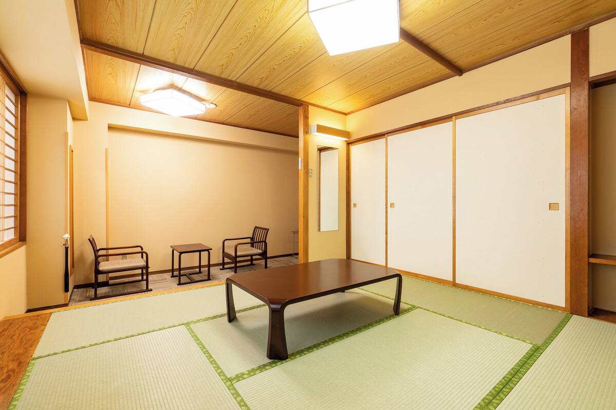 Una habitación japonesa tradicional con suelo de tatami, una mesa baja y puertas correderas.