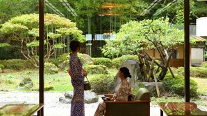 A traditional Japanese garden with stone lanterns, a koi pond, and a wooden bridge. - Ooedo Onsen Monogatari Kounkaku (Osaki)