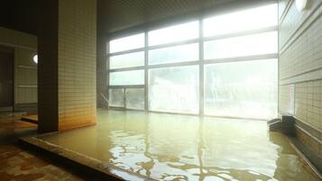 A large indoor pool with clear glass windows, tiled walls, and a tiled floor.