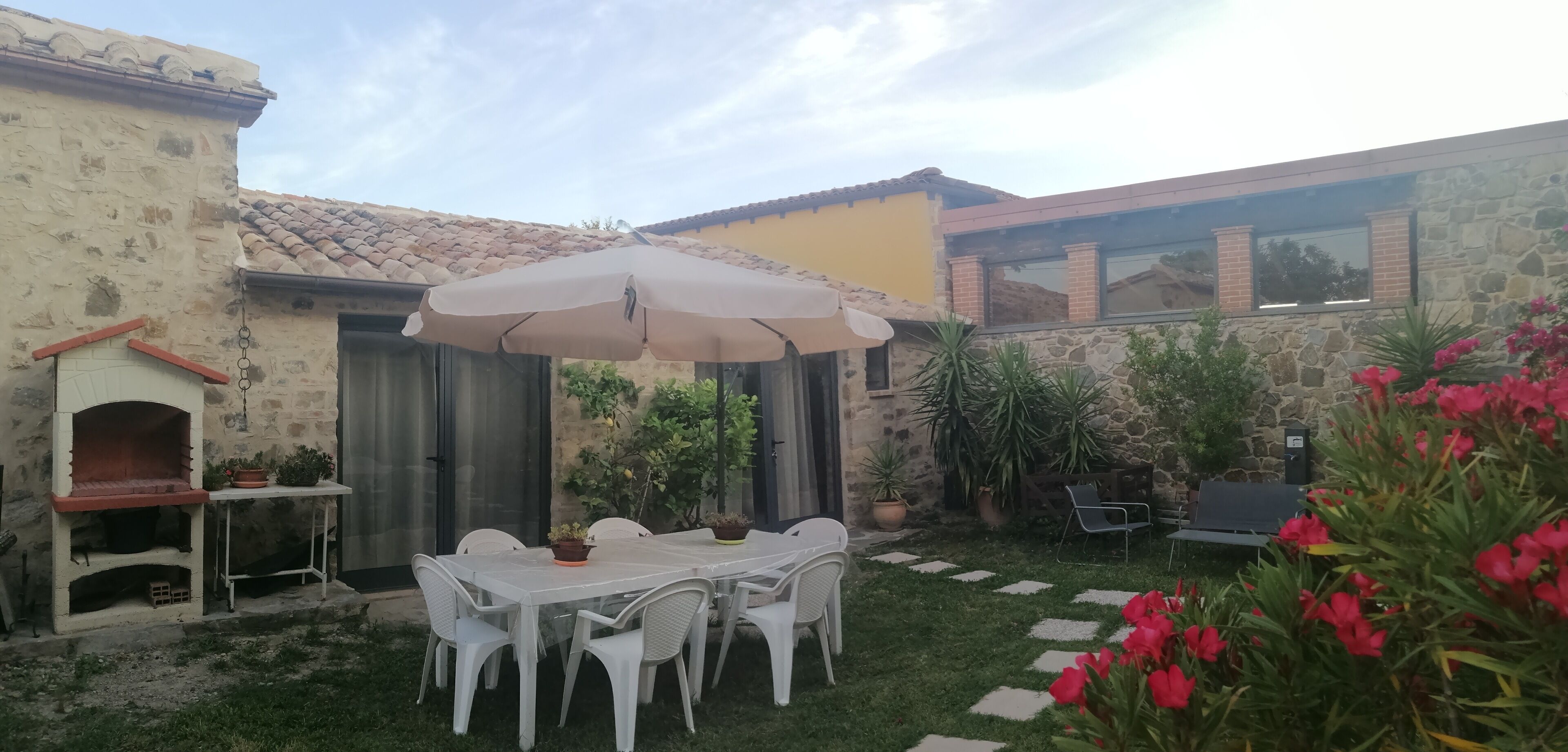 A patio with a table and chairs, surrounded by potted plants and a stone wall.
