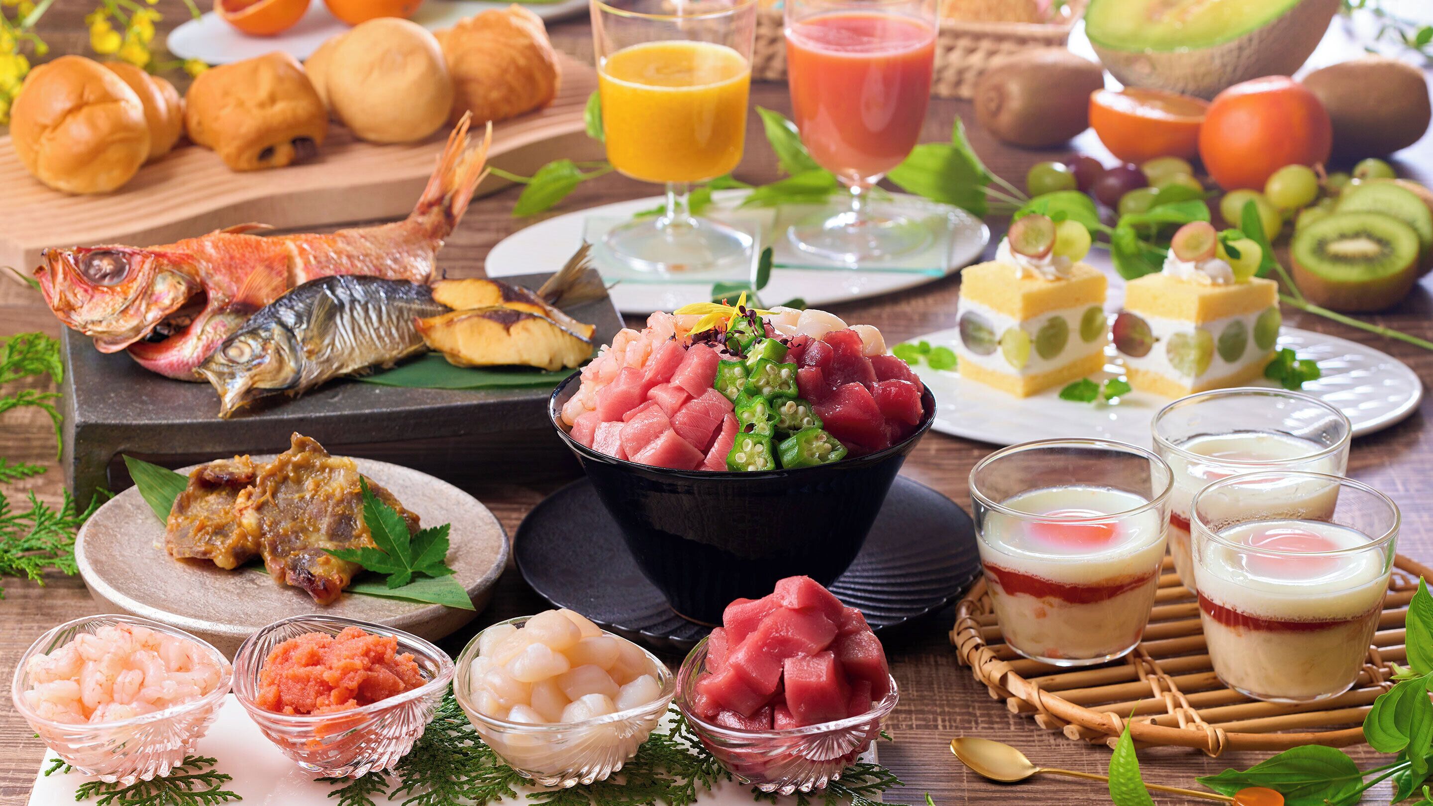 Diversos alimentos como sashimi, frutas y bebidas sobre una mesa de madera.