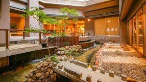 A multi-level indoor garden with a water feature, stone pathways, and seating areas. - Ooedo Onsen Monogatari Masuya (Osaki)