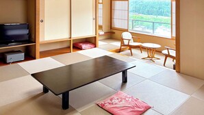 A room with tatami flooring, a low table, a TV, and a view of a forest through a window. - Ooedo Onsen Monogatari Masuya (Osaki)