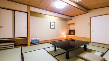 Een traditionele Japanse kamer met tatami vloerbedekking, een lage tafel, kussens en een schuifdeur.