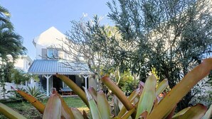 Une maison à l’extérieur blanc, avec un toit bleu et une véranda.
