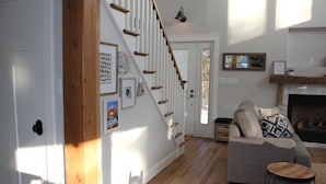A living room with a staircase, a fireplace, and a sofa. - 4-bedroom house in Stanhope - walk to the beach! (York)
