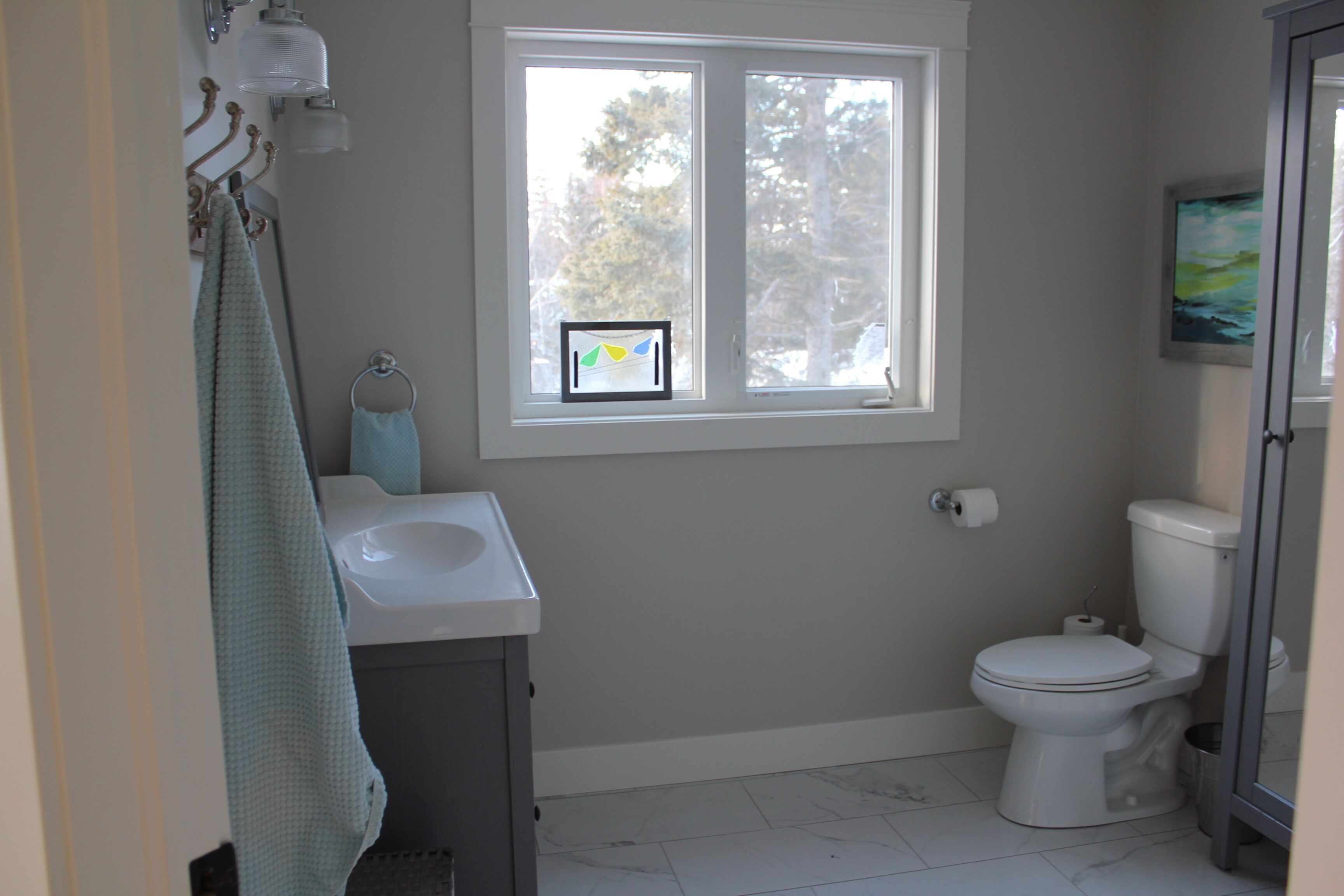 Un baño con inodoro, lavamanos y ventana.