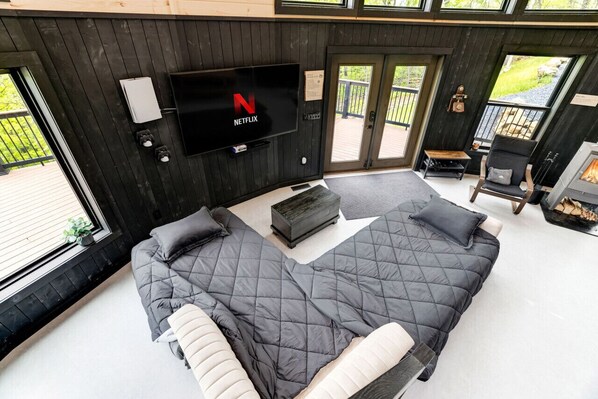 Un dormitorio moderno con una cama grande, un televisor montado en la pared y una chimenea.