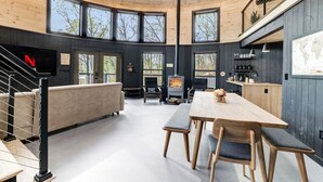 Un interior moderno con techo de madera, ventanas amplias, chimenea, zona de comedor y cocina.