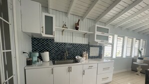 A kitchen with white cabinets, a black and white backsplash, and a window with shutters.
