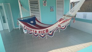 A hammock in a covered outdoor area with a tiled floor and a ceiling fan.