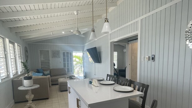 A spacious kitchen with a central island, white cabinetry, and a dining area with chairs.