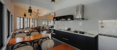 A modern kitchen with a dining area, featuring a wooden table, chairs, and pendant lighting.
