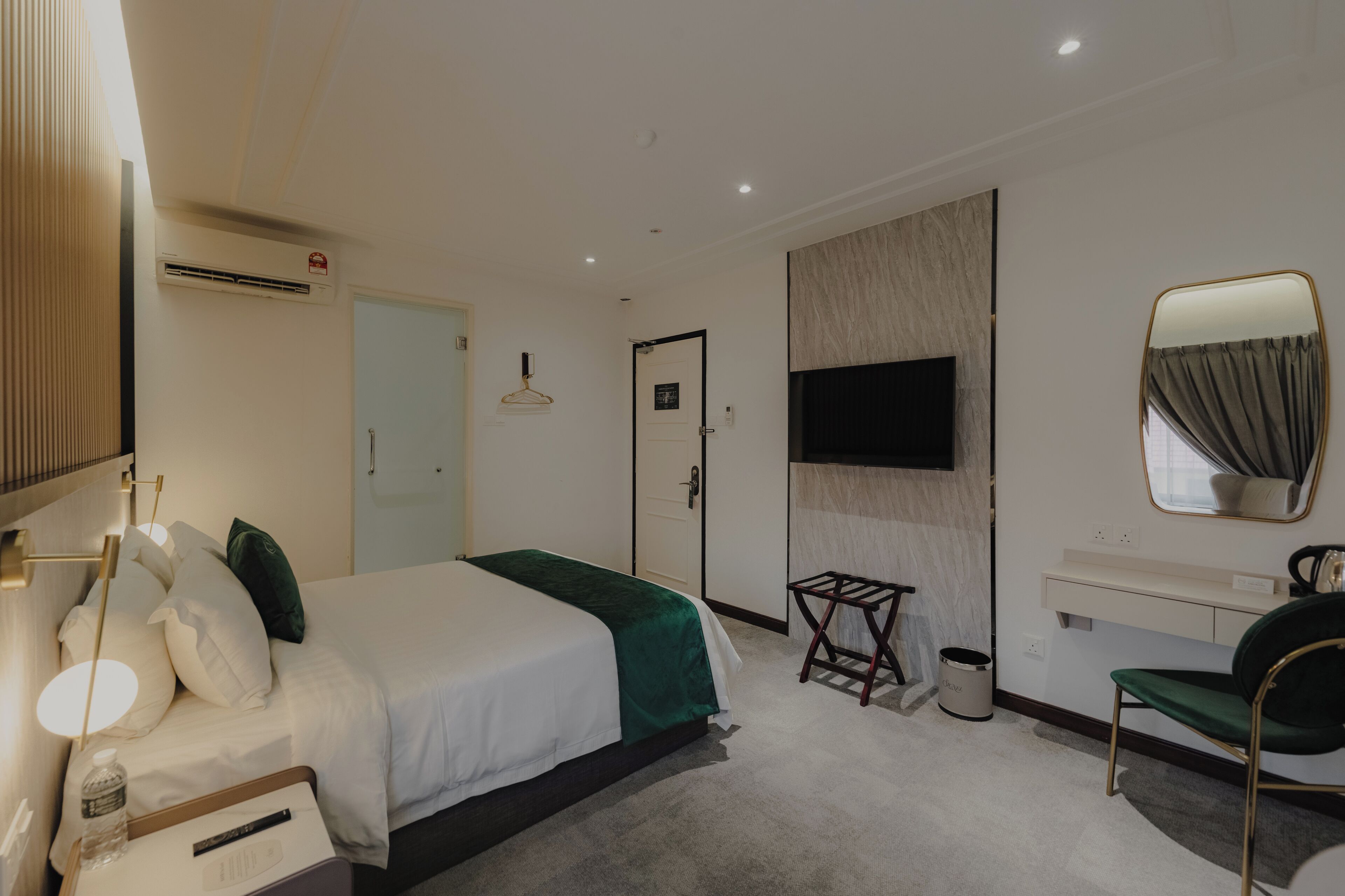 Una moderna camera d'albergo con un letto grande, una scrivania, una sedia, una televisione e uno specchio.