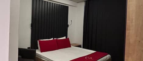A modern bedroom with a bed, a wooden desk, and a chair.