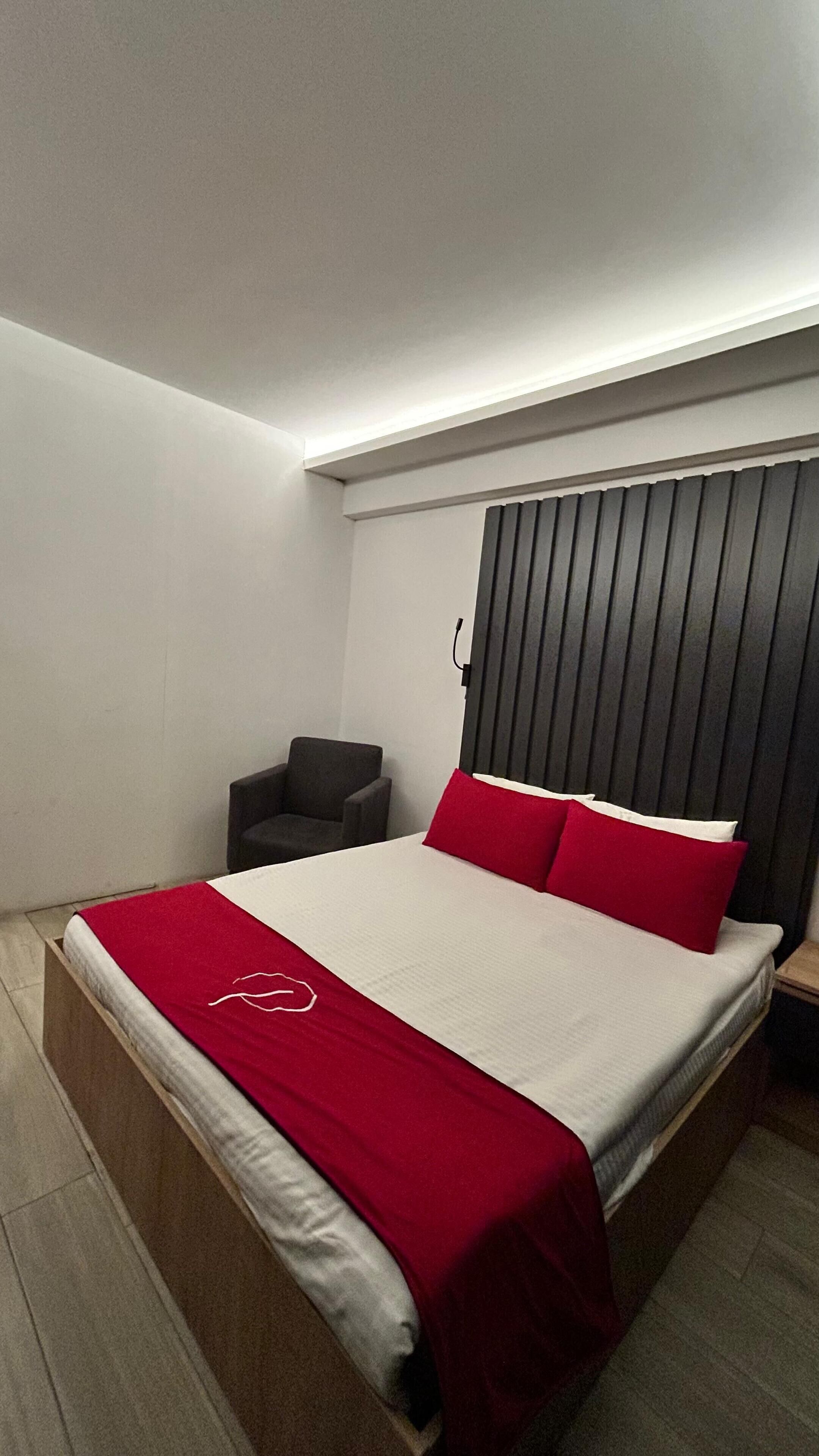 A modern bedroom with a bed, a chair, and a wooden headboard.