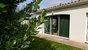 A house with a large sliding glass door, a small garden, and a tiled roof. - Casa Upupa  (Montreuil)