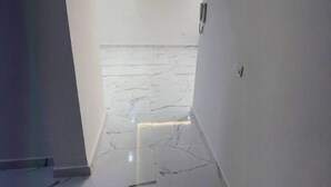 Un passadís amb parets blanques i un sòl de marbre brillant.
